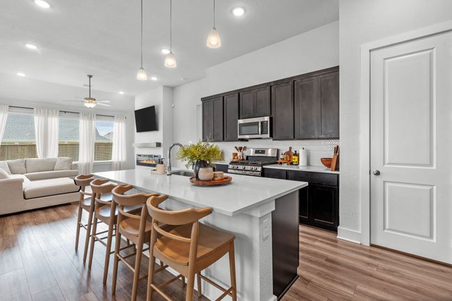 Kitchen featuring open floor plan, a breakfast bar area, decorative light fixtures, stainless steel appliances, and a center island with sink | Image 12