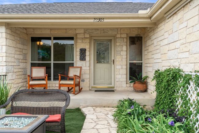 View of exterior entry featuring a porch, a shingled roof, and stone siding | Image 4
