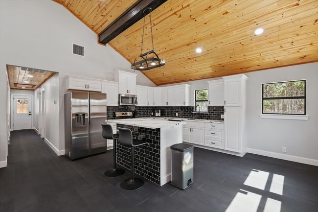 Kitchen featuring a sink, white cabinetry, visible vents, appliances with stainless steel finishes, and tasteful backsplash | Image 19