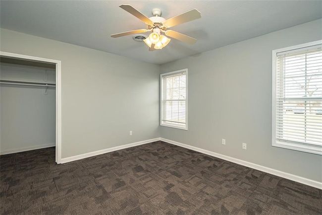 Unfurnished bedroom featuring multiple windows, baseboards, and dark colored carpet | Image 25