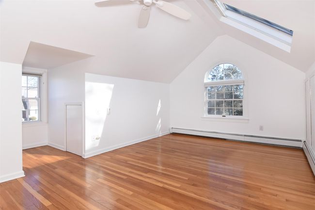 Upstairs bedroom featuring a baseboard heating unit, lofted ceiling with skylight, plenty of natural light, and light wood-type flooring | Image 16