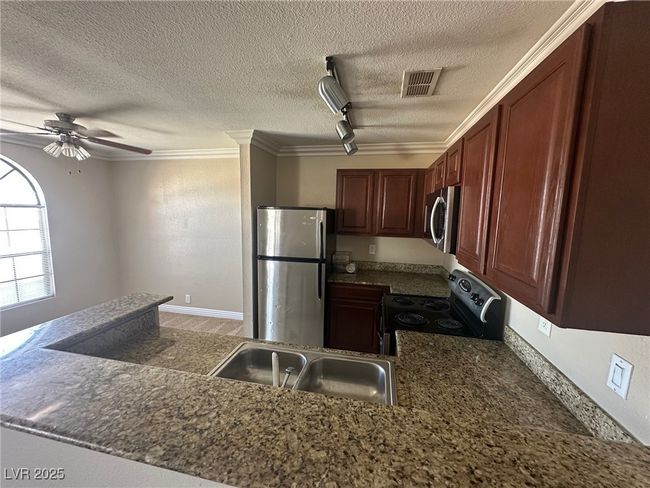 Kitchen featuring stainless steel appliances, ceiling fan, a sink, visible vents, and a textured ceiling | Image 6
