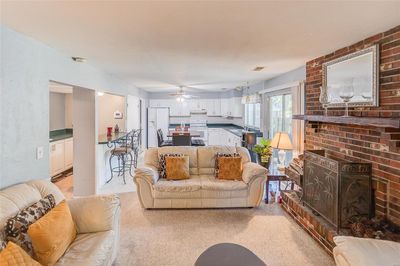 Carpeted living room featuring ceiling fan, sink, and a fireplace | Image 2