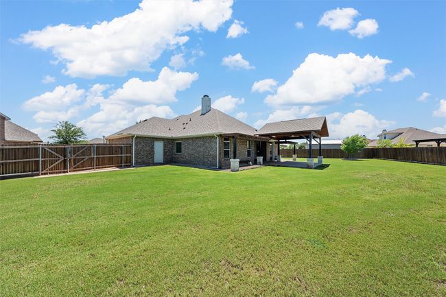 Back of property with a fenced backyard, a patio, brick siding, and a chimney | Image 33