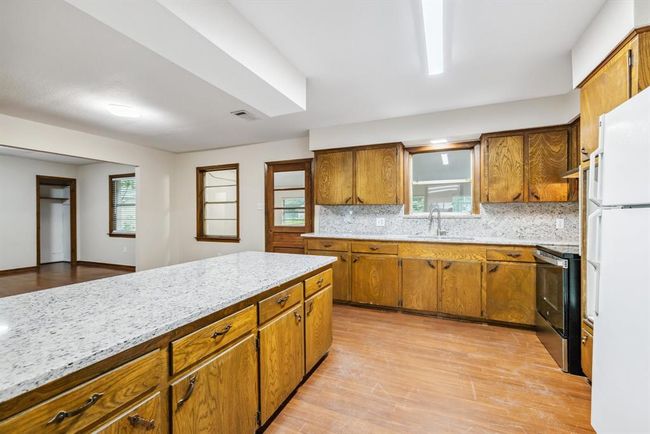 Kitchen offers updated granite, updated faucet, undermount sink and updated range. Sink window looks into covered enclosed back porch. | Image 14