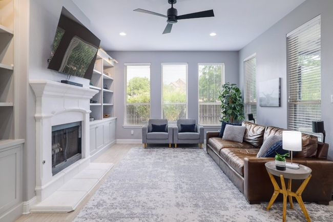 Living area featuring wood finished floors, a ceiling fan, a fireplace with raised hearth, baseboards, and recessed lighting | Image 4
