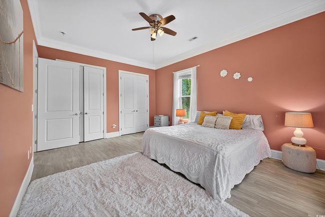 Bedroom featuring two closets, wood finished floors, crown molding, and a ceiling fan | Image 38