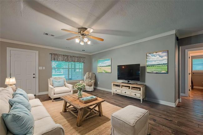 Open concept main living area offers tile flooring, crown molding, and loads of natural lighting from a large picture window overlooking the sunroom and lush backyard.(AI photo) | Image 6