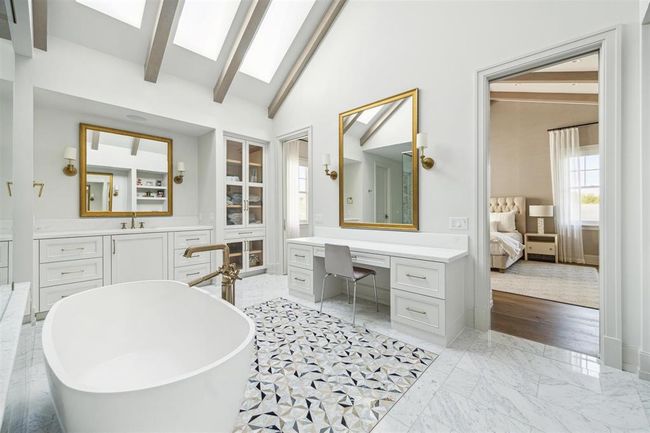 Every detail has been meticulously crafted in this exquisite spa-like bath, featuring a luxurious soaking tub and elegant Carrara marble flooring. Soaring ceilings with striking skylights bathe the space in natural light, creating a serene and tranquil oasis. | Image 16