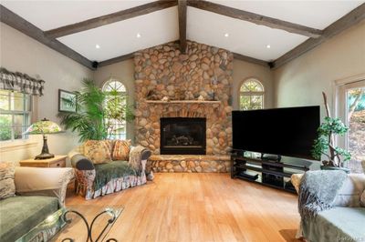 Living room with a wealth of natural light, hardwood / wood-style floors, and a fireplace | Image 1