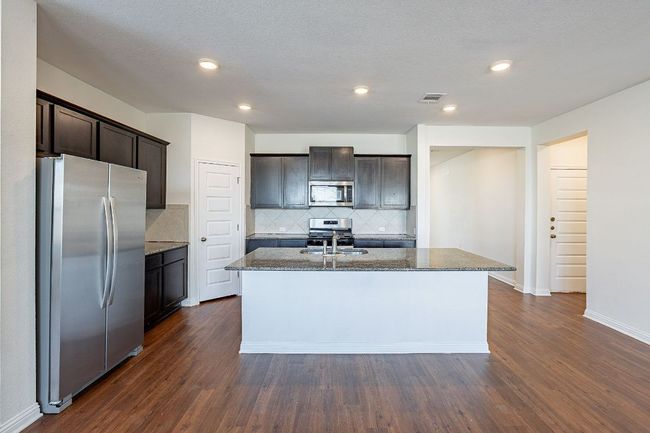 Kitchen featuring a center island with sink, dark wood-style floors, visible vents, dark brown cabinets, and appliances with stainless steel finishes | Image 5