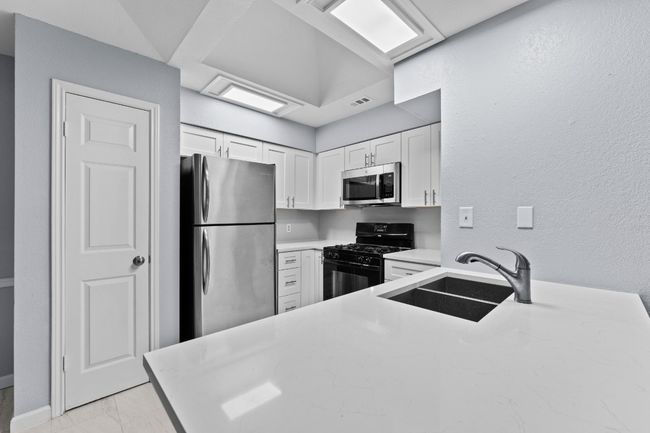 Kitchen featuring stainless steel appliances, white cabinetry, light marble finish floors, and light stone countertops | Image 16