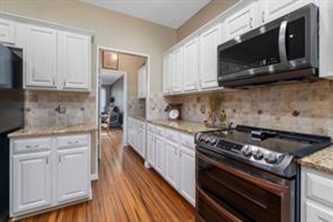 Kitchen featuring white cabinets, dark wood-style flooring, and appliances with stainless steel finishes | Image 19