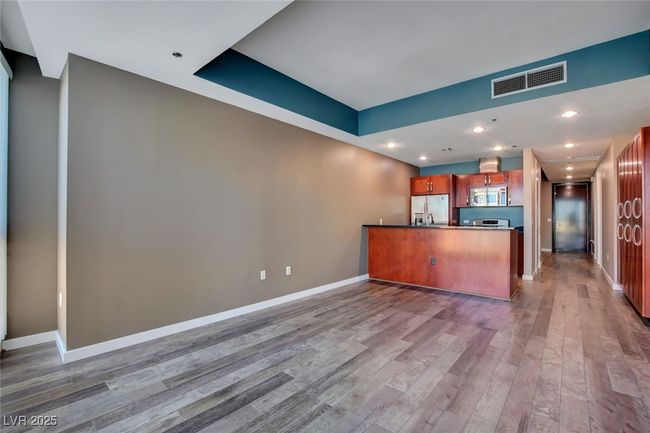 Kitchen with light wood finished floors, baseboards, visible vents, brown cabinetry, and appliances with stainless steel finishes | Image 6