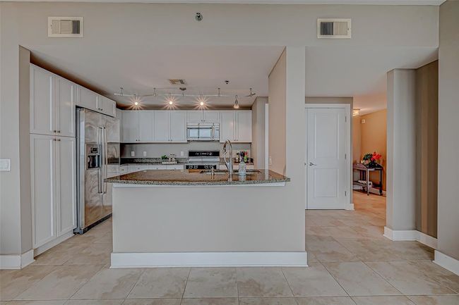Spacious open-concept kitchen with elegant white cabinets, seamlessly connected to the den. | Image 7