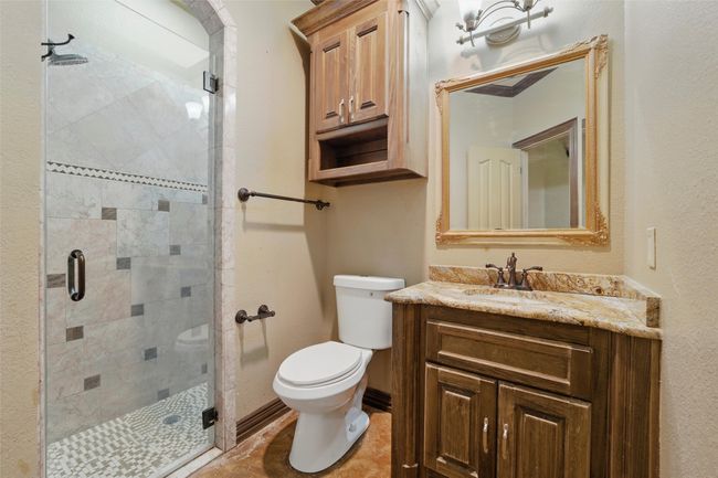 Bathroom featuring toilet, vanity, a stall shower, and baseboards | Image 38