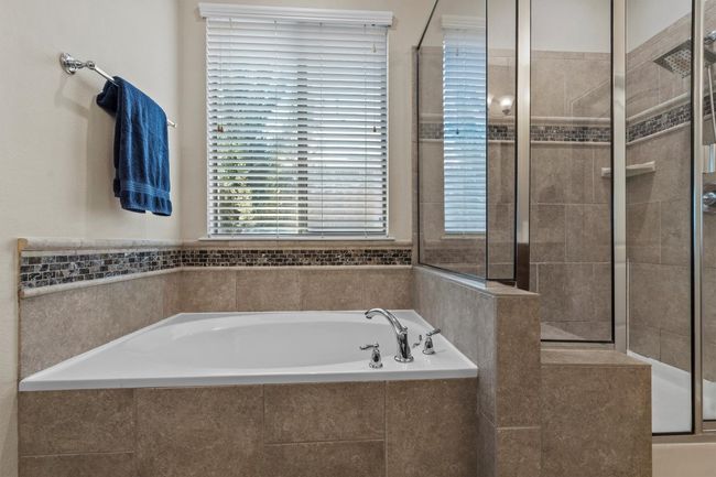 A luxurious soaking tub and glass-enclosed shower are accented with designer tilework and flooded with natural light. | Image 22