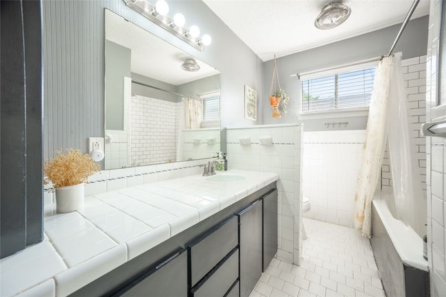 Full bathroom with tile patterned floors, toilet, a wainscoted wall, and tile walls | Image 16