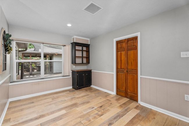 This room features beautiful flooring, a large window for natural light, and a door leading to the laundry room. A built-in cabinet adds storage and character- Perfect for a cozy, functional space! | Image 12