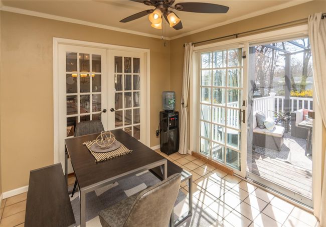 Dining room with crown molding, light tile patterned floors, ceiling fan, french doors, and baseboards | Image 8