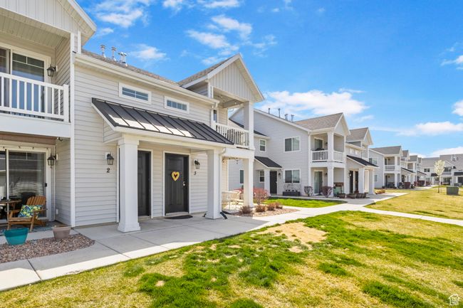 View of front of house featuring a front yard, metal roof, a balcony, a residential view, and a standing seam roof | Image 4