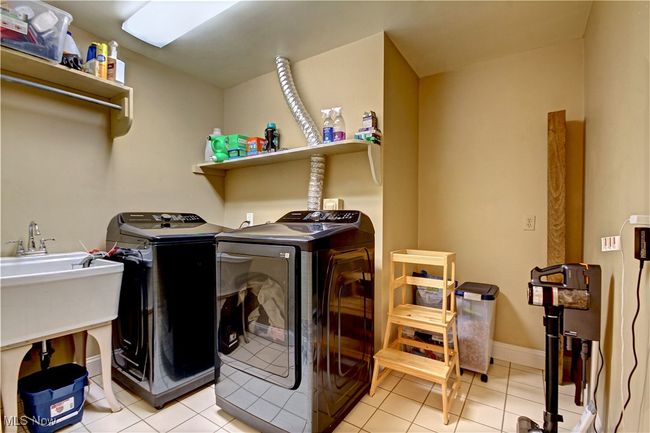 Laundry area with washing machine and clothes dryer and light tile patterned floors | Image 22