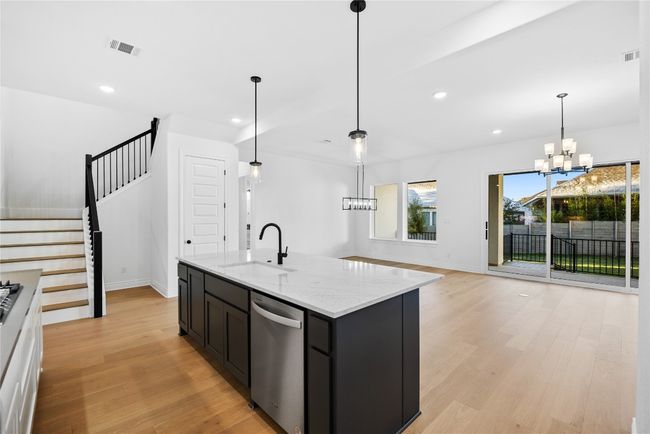 Kitchen with stainless steel appliances, light wood finished floors, a chandelier, recessed lighting, and light stone counters | Image 23