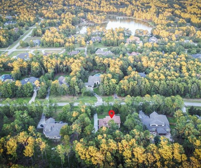 The home is surrounded by lush, mature trees, and is located near a serene lake within the prestigious Benders Landing. | Image 6