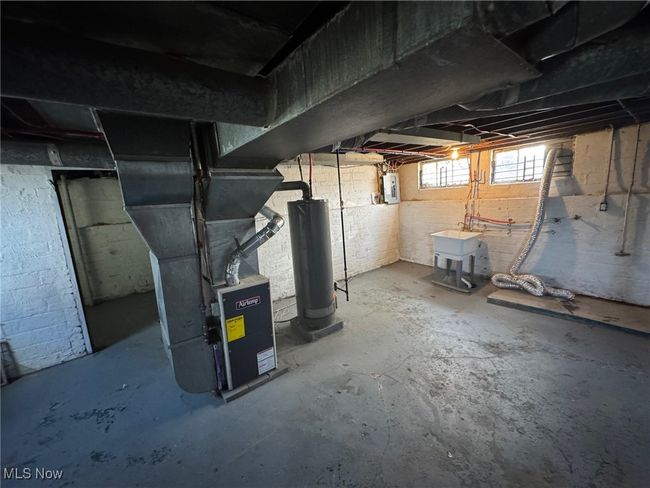 Basement with gas water heater, electric panel, heating unit, and a sink | Image 17