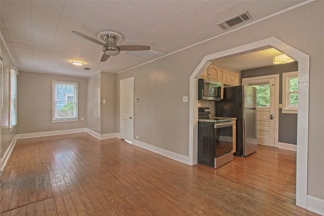Empty room featuring arched walkways, hardwood / wood-style flooring, ceiling fan, and crown molding | Image 12