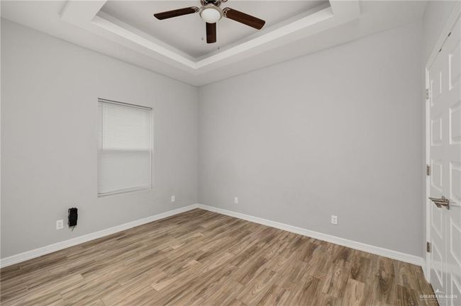 Unfurnished room featuring a tray ceiling, a ceiling fan, light wood-style flooring, and baseboards | Image 8