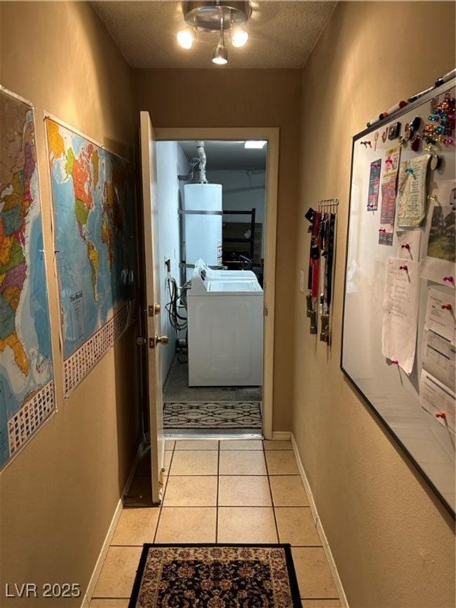 Corridor featuring washer / dryer, light tile patterned flooring, water heater, and a textured ceiling | Image 39