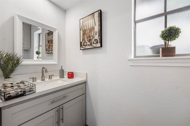 This 1/2 bathroom features a vanity with a sleek countertop, a mirror, and stylish fixtures. Natural light filters through a frosted window | Image 22