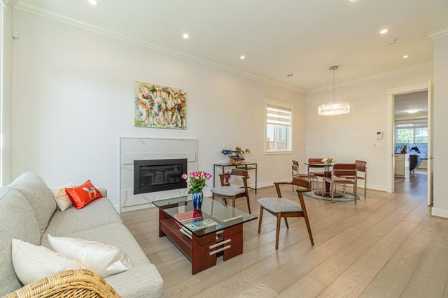 Living room with light wood-style flooring, crown molding, recessed lighting, a glass covered fireplace, and baseboards | Image 4