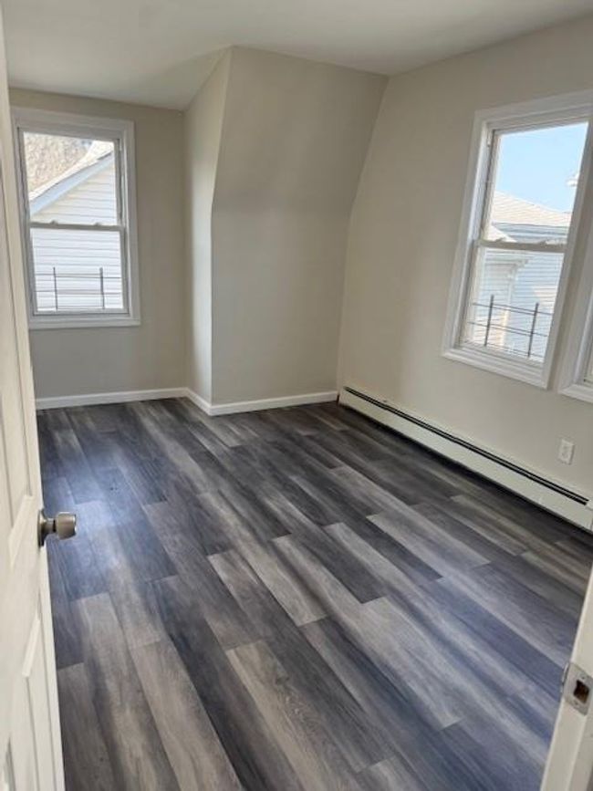 Additional living space featuring a baseboard heating unit and dark wood-type flooring | Image 10