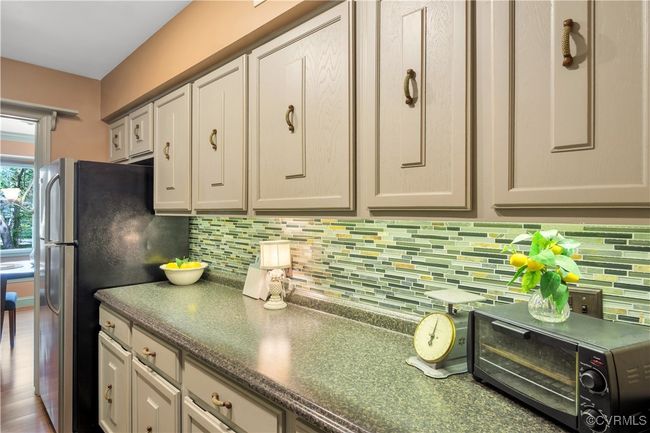Kitchen with dark stone countertops, a toaster, freestanding refrigerator, and decorative backsplash | Image 8