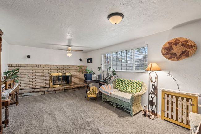 Carpeted living room featuring a ceiling fan, a textured ceiling, and a fireplace | Image 19
