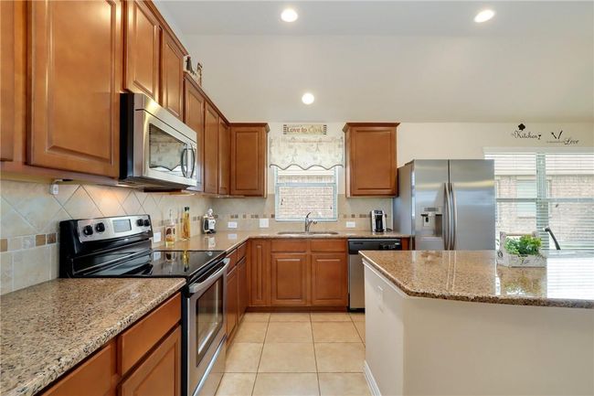 Kitchen with stainless steel appliances, a sink, light stone countertops, tasteful backsplash, and recessed lighting | Image 5