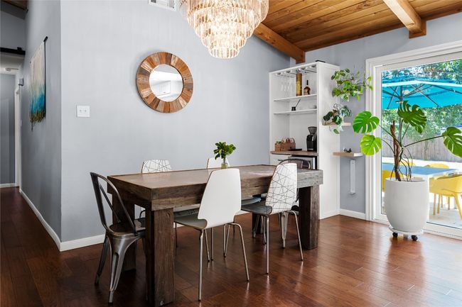 Dining room with a wood ceiling with exposed beams, wood finished floors, a chandelier, and a barn door | Image 7