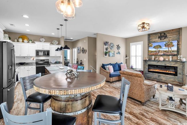 Dining area featuring light wood-type flooring, recessed lighting, visible vents, a notable chandelier, and a glass covered fireplace | Image 9