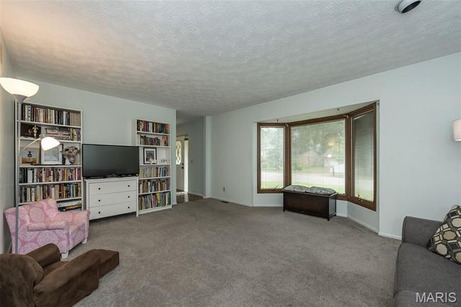 Carpeted living area with a textured ceiling and baseboards | Image 7