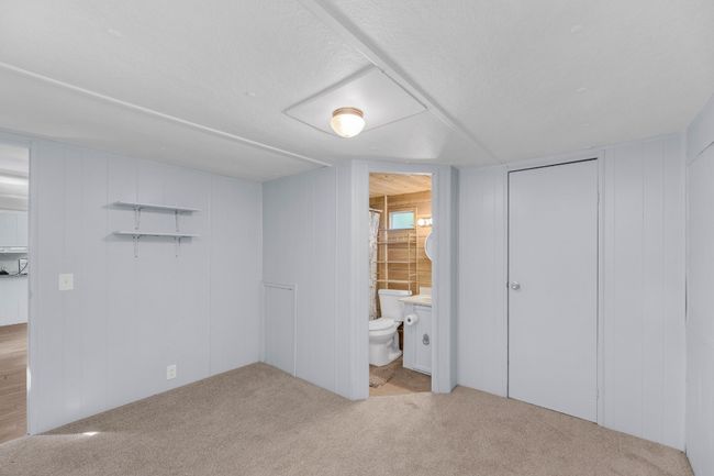Unfurnished bedroom featuring carpet floors, ensuite bathroom, and a decorative wall | Image 23