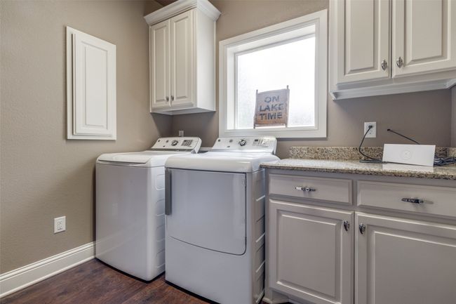 Laundry area with dark wood-type flooring, cabinets, and washing machine and dryer | Image 28