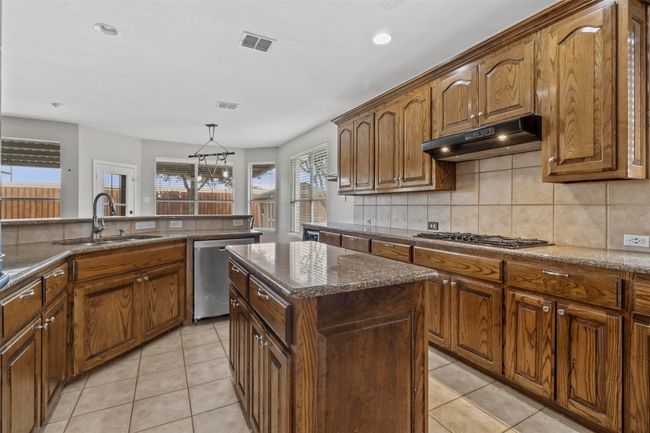 Kitchen featuring stainless steel dishwasher, gas stovetop, decorative backsplash, under cabinet range hood, and recessed lighting | Image 9