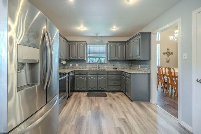Kitchen featuring stainless steel appliances, gray cabinets, light wood finished floors, and backsplash | Image 9
