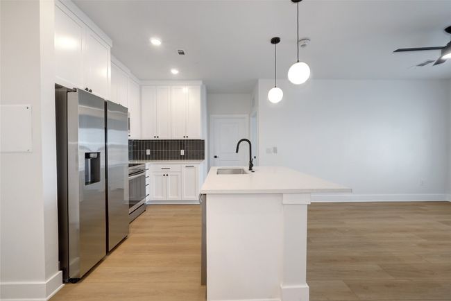 Kitchen with appliances with stainless steel finishes, a sink, light wood-style floors, light countertops, and recessed lighting | Image 4