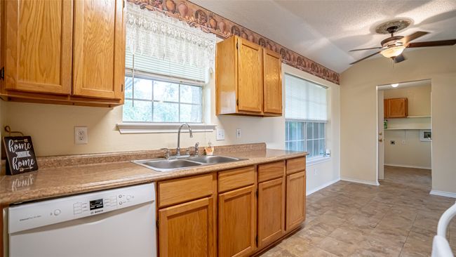 Kitchen with dishwasher, a sink, a ceiling fan, light countertops, and a textured ceiling | Image 8