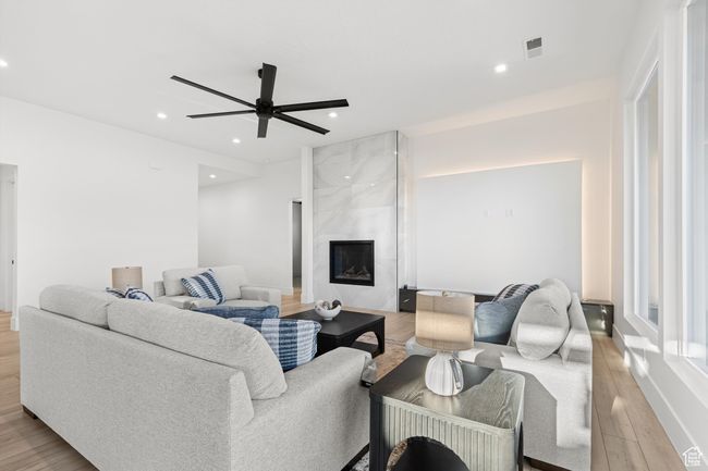 Living room featuring light wood-type flooring, a ceiling fan, visible vents, recessed lighting, and a premium fireplace | Image 12