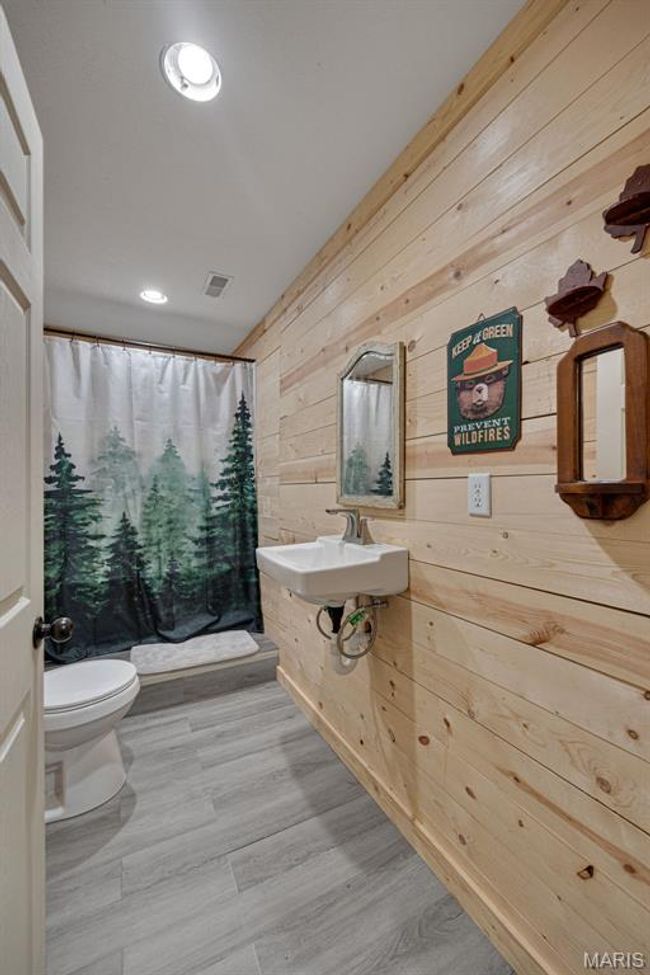 Bathroom featuring toilet, wooden walls, a shower with shower curtain, a sink, and recessed lighting | Image 17