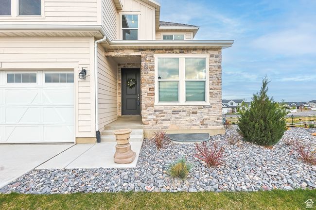 View of exterior entry featuring stone siding and an attached garage | Image 47
